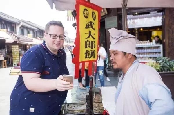 외국인 한 명이 거리 음식을 사기 위해 모바일로 결제하고 있다.