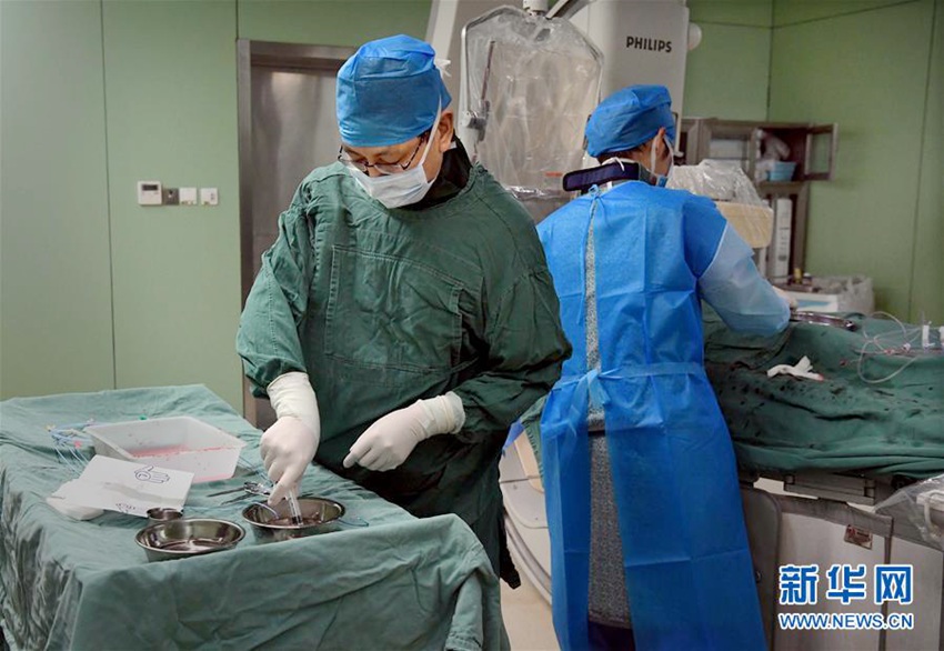 3월 22일, 허난(河南, 하남)성 인민병원 심장혈관 내과 천옌(陳岩, 좌측) 주임의사가 방사선 방호복을 입은 채, 도관실(導管室)에서 수술 기구를 준비하고 있다.