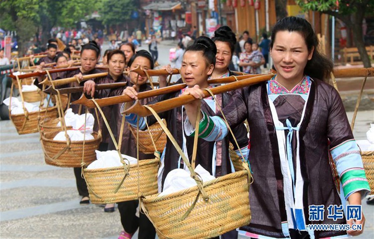 4월 20일 구이저우(貴州, 귀주)성 리핑(黎平)현 자오싱(肇興) 동족(侗族) 마을, 동족 여성들이 우미판(烏米飯, 오미밥)을 친구들에게 선물하기 위해 어깨에 메고 걸어가는 모습