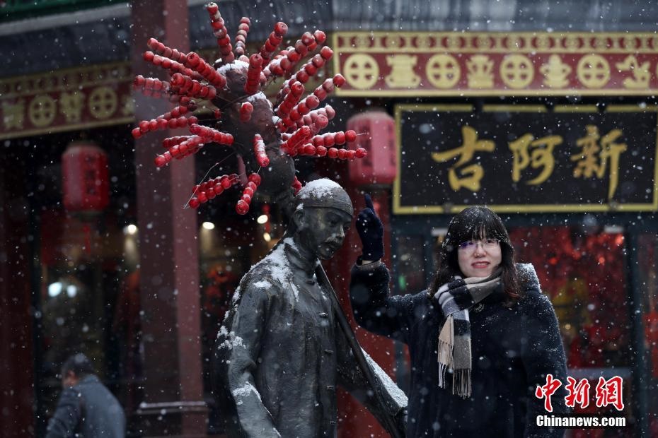 2월 12일 한 관광객이 빙탕후루(冰糖葫蘆) 상인 조각상 앞에서 기념사진을 찍고 있다. [촬영: 중국신문사 한하이단(韓海丹) 기자]