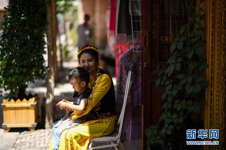 카스고성(喀什古城) 관광지에서 현지인이 아이를 안은 채 집 앞에 앉아 햇볕을 쬐고 있다. [사진 출처: 신화망]
