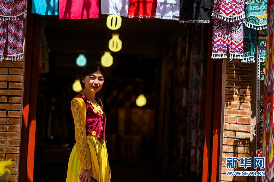 카스고성(喀什古城) 관광지 모 상점 앞에 전통의상을 입은 직원이 서 있다.  [사진 출처: 신화망]