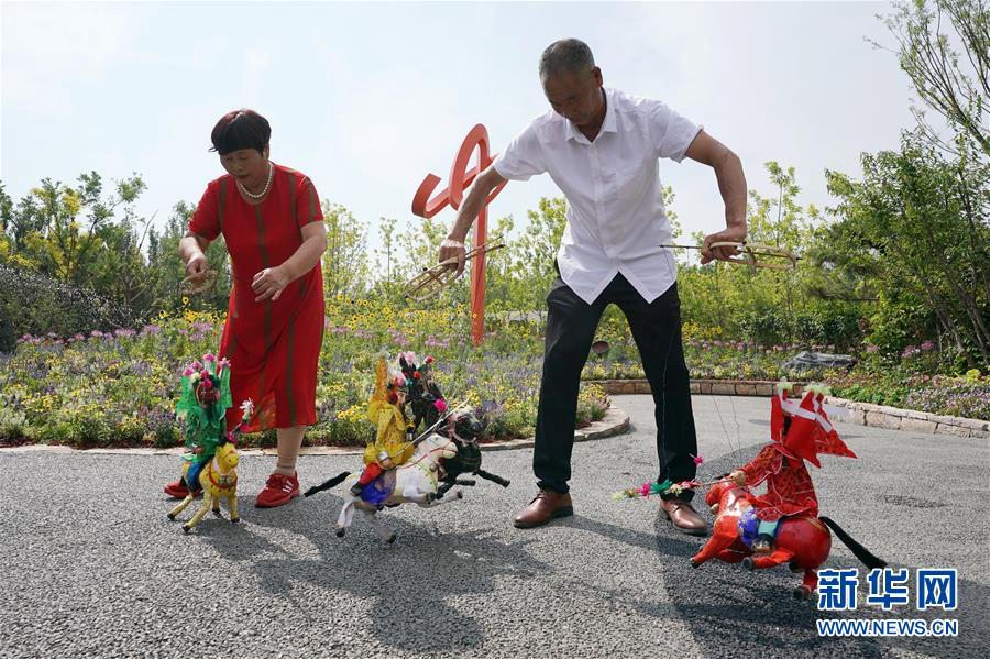 6월 23일 허난(河南)성 바오펑(寶豐)현에서 온 러우옌쥔(婁艶俊, 오른쪽) 씨가 베이징 세계원예박람회 허난관에서 전통 인형극 ‘삼영전여포(三英戰呂布)’ 공연을 펼치고 있다. [사진 출처: 신화망]
