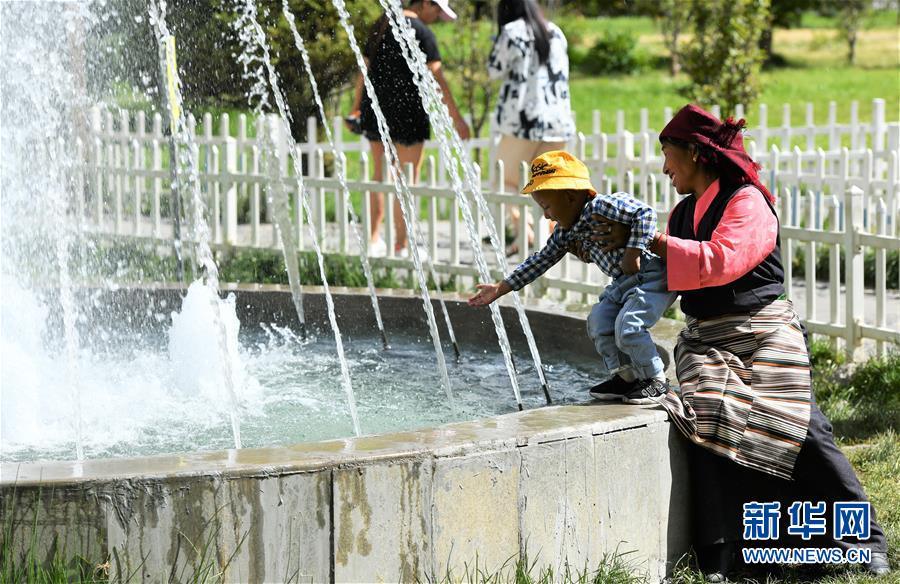 라싸(拉薩)시 쭝자오루캉(宗角祿康) 공원, 한 어린이가 어머니와 함께 물놀이를 하고 있다.  [사진 출처: 신화망]