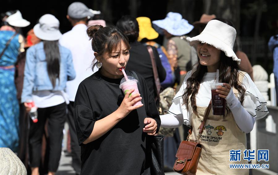 젊은 여성 두 명이 라싸(拉薩)시 길거리에서 차가운 음료수를 마시며 더위를 식히고 있다. [사진 출처: 신화망]