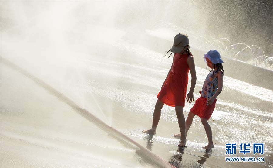 6월 26일 어린이 두명이 오스트리아 비엔나 슈바르첸베르크 광장에서 물놀이를 하며 더위를 피하고 있다. [사진 출처: 신화망]
