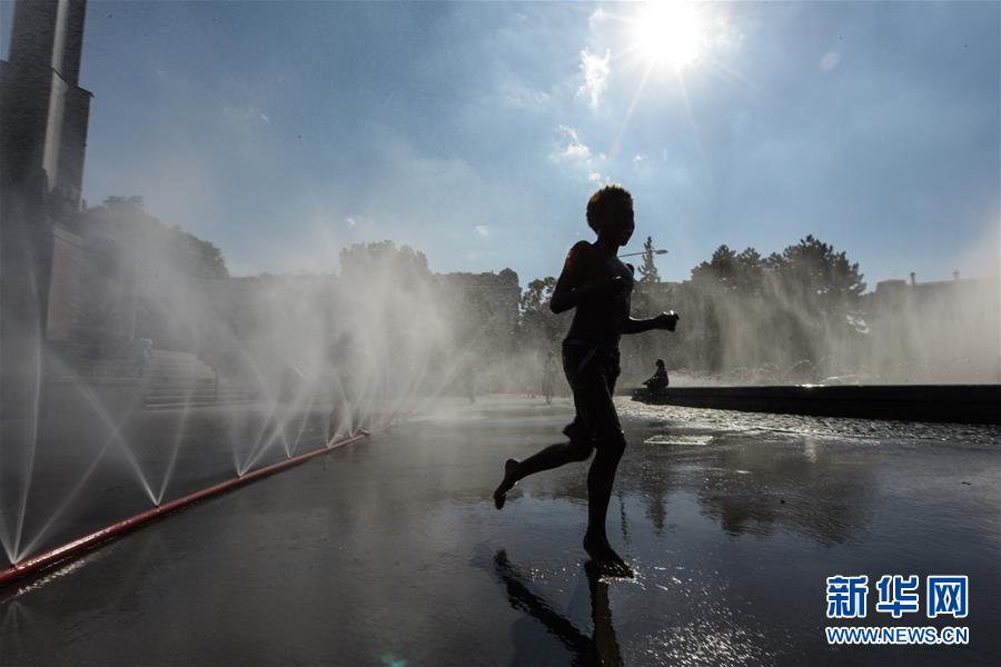 6월  26일 한 어린이가 오스트리아 비엔나 슈바르첸베르크 광장에서 물놀이를 하며 더위를 피하고 있다. [사진 출처: 신화망]