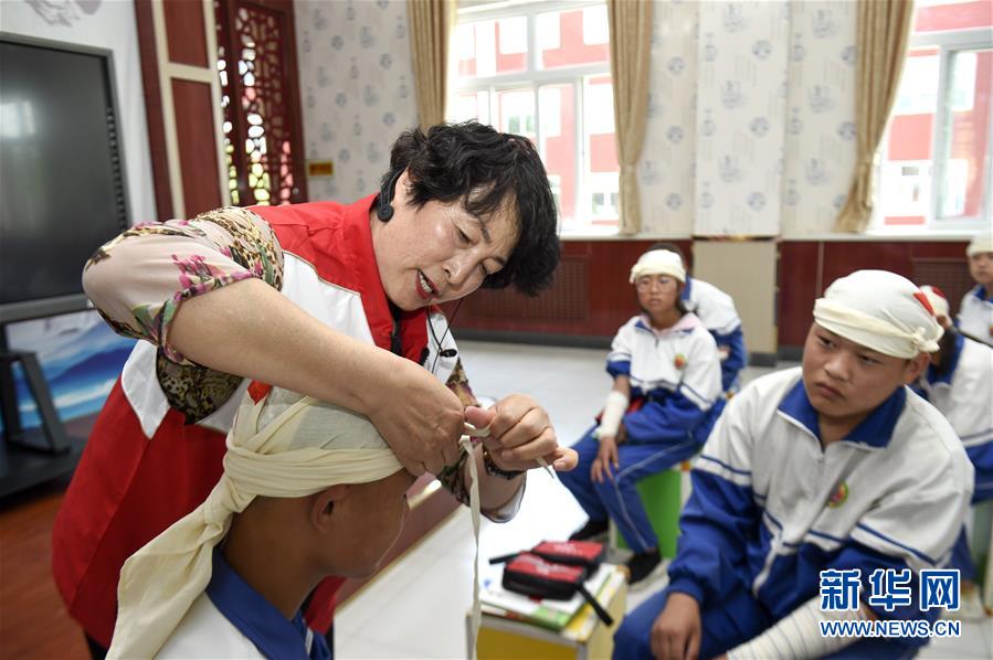 인촨(銀川)시 16중학교 학생들이 중국 적십자기금회 응급의료진(왼쪽 1번째)으로부터 삼각건 붕대법에 대해 배우고 있다. [사진 출처: 신화망]