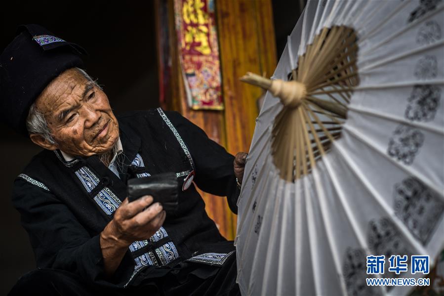 장룽화(張榮華) 노인이 꽃우산에 무늬를 새기고 있다. [사진 출처: 신화망]