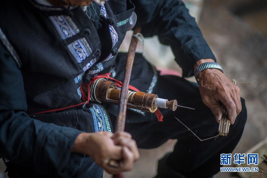 장룽화(張榮華) 노인이 전용 도구를 사용해 우산살에 구멍을 뚫고 있다. [사진 출처: 신화망]