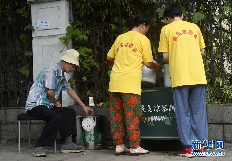 7월 14일, 창밍쓰샹(長明寺巷) 주택단지 거주민들이 구중건(顧忠根, 왼쪽) 씨와 함께 행인들에게 무료로 량차(凉茶)를 나눠주고 있다. [사진 출처: 신화망]