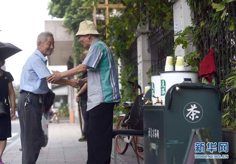 7월 14일, 구중건(顧忠根, 오른쪽) 씨와 무료 량차(凉茶)를 받은 한 노인이 악수를 하며 인사를 나누고 있다. [사진 출처: 신화망]