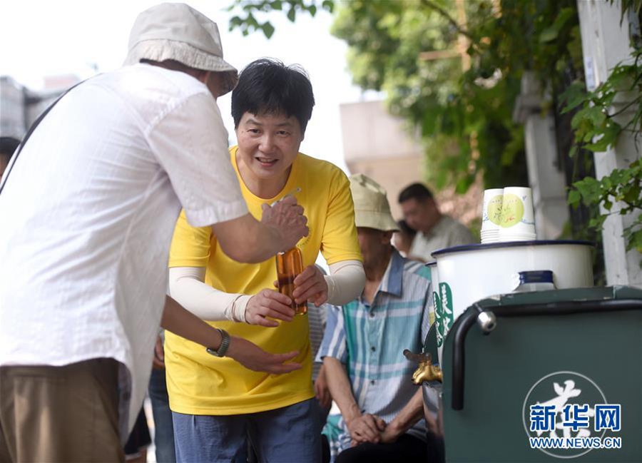 7월  14일, 자원봉사자로 나선 창밍쓰샹(長明寺巷) 주택단지 거주민 선서펑(沈社鳳) 씨가 행인에게 무료 량차(凉茶)를 나눠주고 있다. [사진 출처: 신화망]