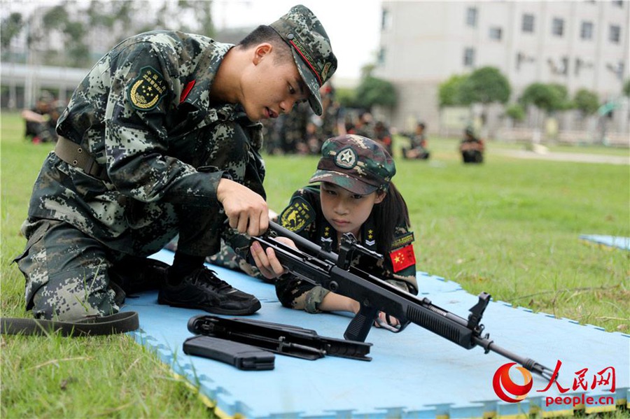 무장경찰 바이써(百色) 지대(支隊) 훈련장, 무장경찰 대원이 어린이에게 총기 구조에 대해 설명하고 있다. [사진 출처: 인민망]