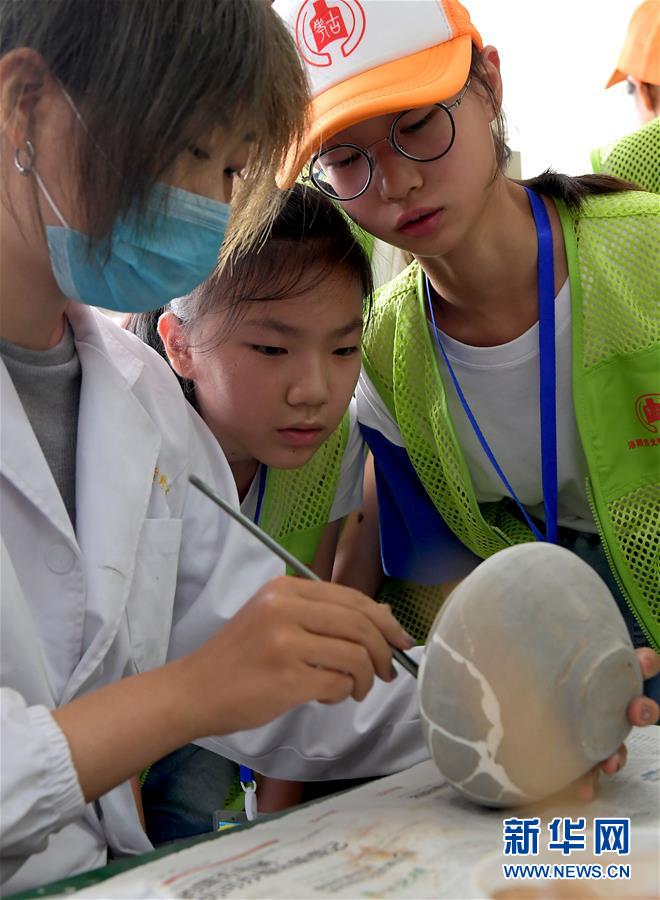8월 1일 뤄양(洛陽)시, ‘나는 어린이 고고학자입니다’ 하계캠프에 참가한 어린이 대원들이 뤄양시 고고학연구원 문화재복원센터 직원이 문화재를 복원하는 모습을 바라보고 있다. [사진 출처: 신화망]