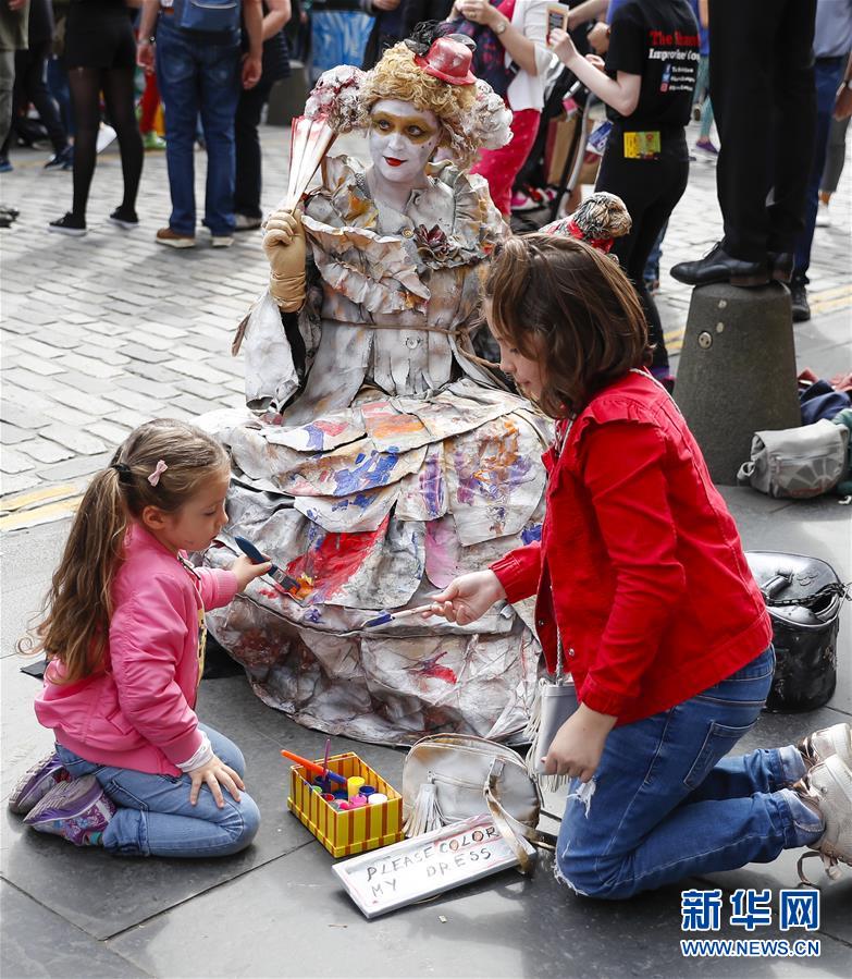 4일 영국 스코틀랜드 에든버러에서 아이들이 길거리 예술가의 치마에 색을 칠하고 있다. [사진 출처: 신화망]