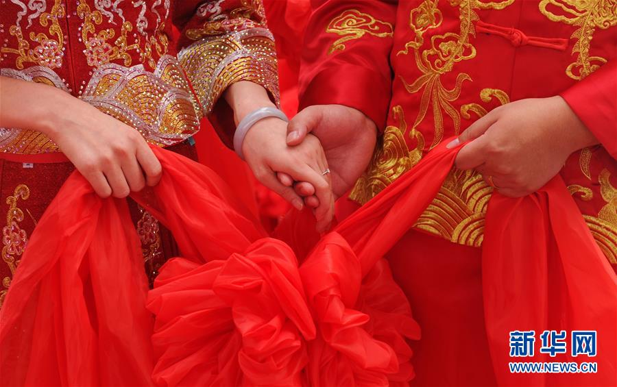 8월 6일 황화(黃驊)시 난하이공원(南海公園) 합동결혼식장, 신혼부부가 홍수구(紅繡球)를 들고 양손을 맞잡고 있다. [사진 출처: 신화망]