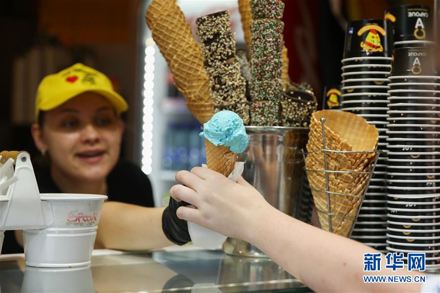 지난달 24일 벨기에 브뤼셀에서 한 상점의 직원이 고객에게 아이스크림을 판매하고 있다. [사진 출처: 신화망]