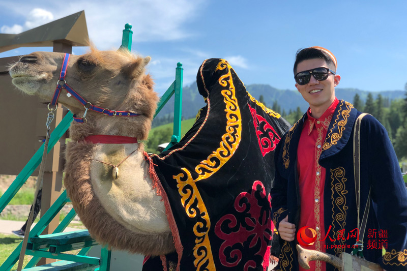 카자흐족(哈薩克族) 전통의상을 입은 인민망 기자가 나라티(那拉提)초원에서 낙타와 기념사진을 찍는 모습 [사진 출처: 인민망]