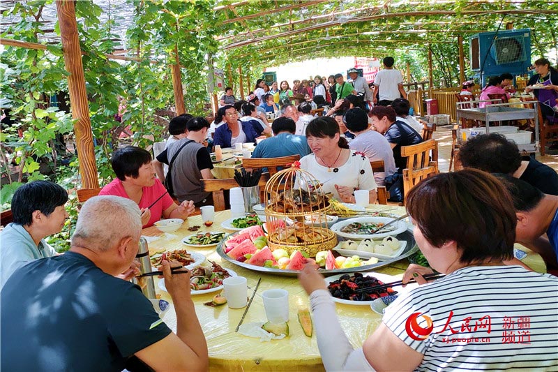 포도정원 아래서 신장(新疆) 음식을 먹는 관광객들 [사진 출처: 인민망]