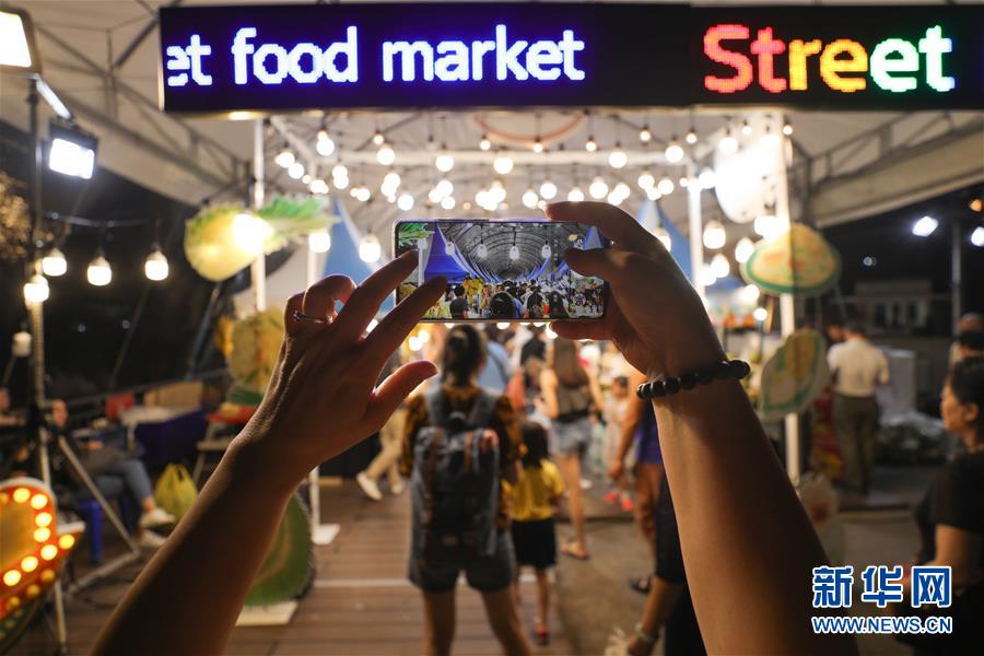 8월 10일 태국 방콕 모 야시장, 관광객이 휴대폰으로 기념사진을 촬영하고 있다. [사진 출처: 신화망]