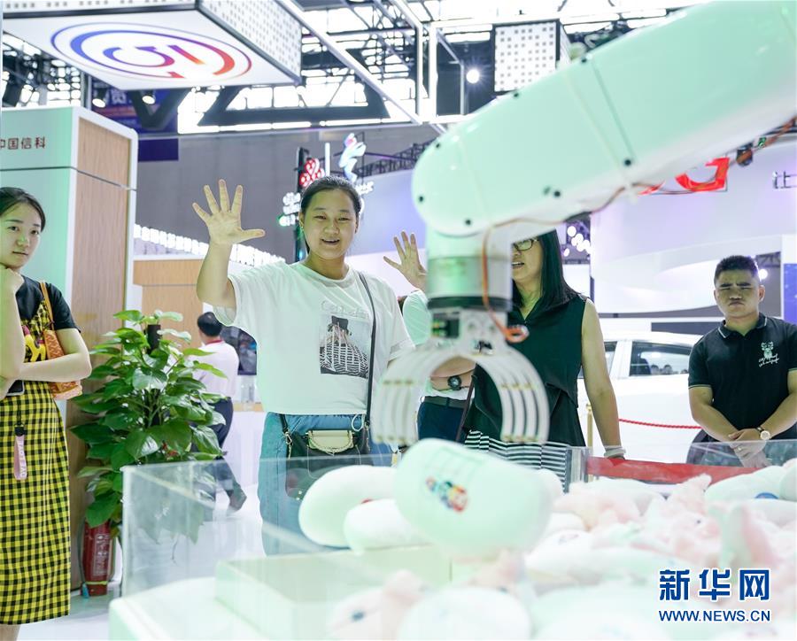 차이나텔레콤(中國電信) 전시 부스를 찾은 참관객들이 5G 원거리 로봇 제어 기술을 체험하고 있다. [사진 출처: 신화망]