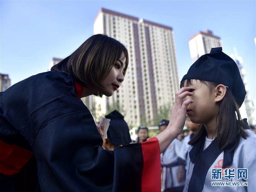 칭하이(靑海)성 시닝(西寧)시 원후이(文匯)초등학교 선생님들이 1학년 신입생들에게 주사계지(朱砂啟智)를 찍어주고 있다. [사진 출처: 신화망]