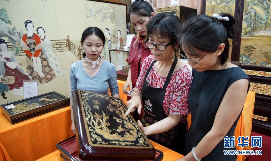 후신(胡昕•오른쪽 두 번째)이 베이징 금칠양감(金漆鑲嵌)유한공사에서 학생들에게 그녀가 창작한 금칠양감 작품에 대해 강의하고 있다. [사진 출처: 신화망]