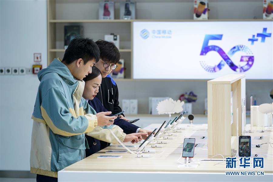 10월 31일 베이징의 한 차이나모바일 영업점에서 점원이 소비자에게 5G 휴대폰을 소개하고 있다. [사진 출처: 신화망]