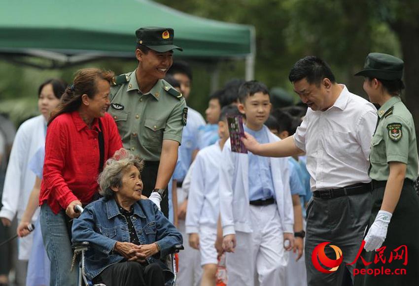 군영 개방 행사에서 마카오 주둔 부대 군인이 노인과 어린이를 도와주고 있다. [5월 2일 촬영/사진 출처: 인민망]