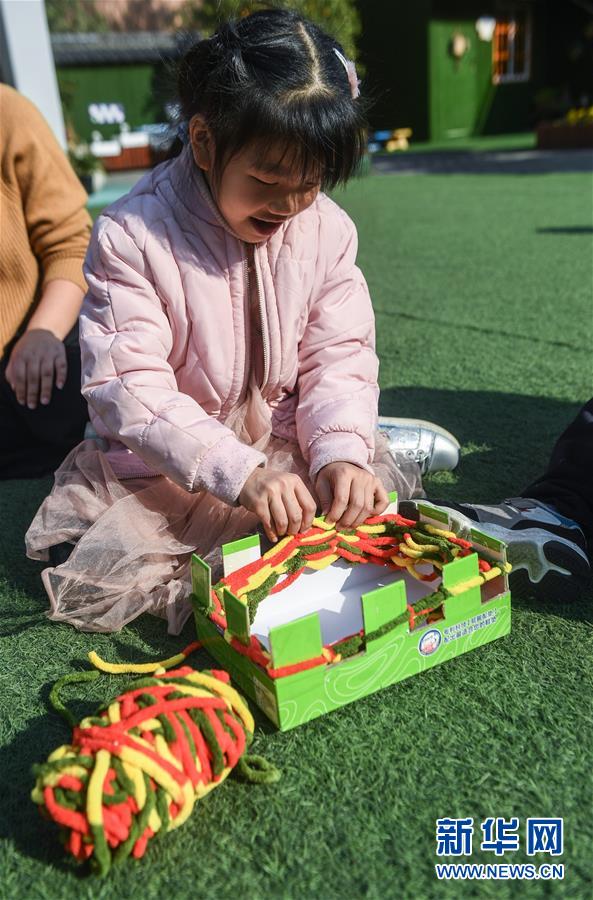 어린 아이들이 종이로 제작한 공구로 사랑의 목도리를 뜨고 있다. [12월 11일 촬영/사진 출처: 신화망]