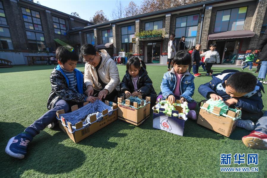 어린 아이들이 선생님의 지도 아래 종이 상자로 제작한 공구로 사랑의 목도리를 뜨고 있다. [12월 11일 촬영/사진 출처: 신화망]