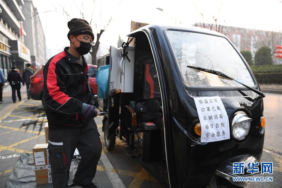 순펑(順豐) 택배원이 베이징시 차오양구에서 택배 배달을 하고 있다. 택배 차량에는 ‘체온 정상, 마스크 착용, 차량 소독, 매일 자체 검사, 안전 서비스’라고 적은 종이가 붙어 있다. [2월 12일 촬영/사진 출처: 신화망]