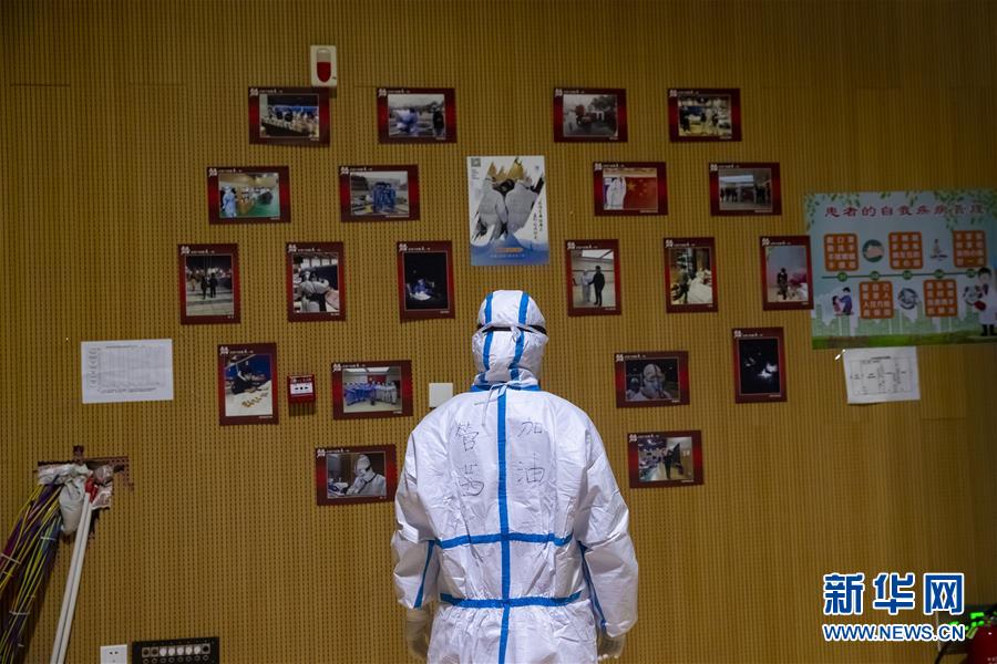 의료진 관첸(管茜)가 팡창의 코로나19 환자와 의료진들이 함께 찍은 사진 게시판을 보고 있다. [사진 출처: 신화망]
