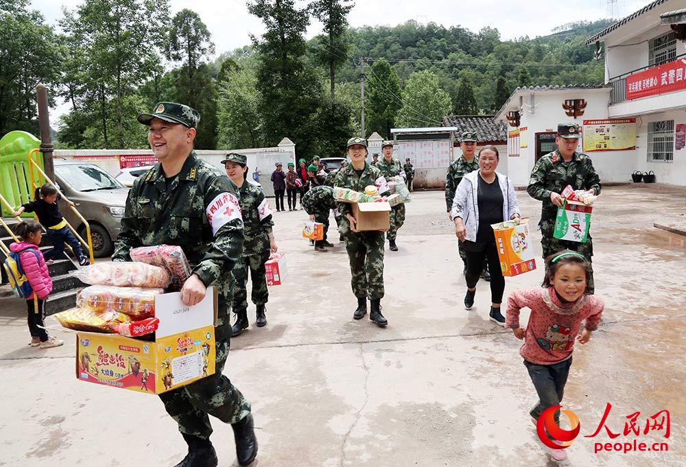 부대 병사들이 어린이들에게 국제아동절 선물을 주고 있다. [사진 출처: 인민망]
