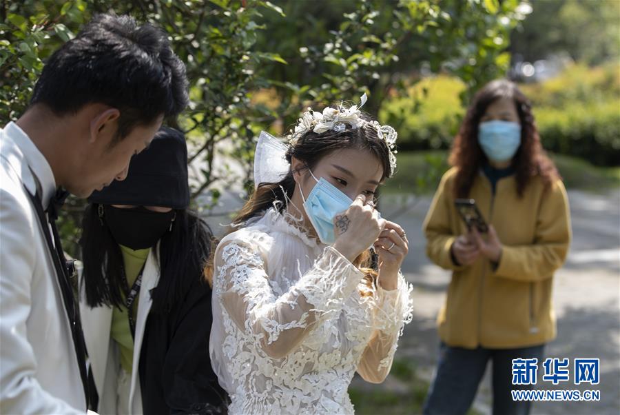 뤄젠(왼쪽 첫 번째)과 청이솽이 우한 장탄공원에서 웨딩 찰영 후 마스크를 쓰고 스튜디오로 돌아갈 준비를 하고 있다. [4월 12일 촬영/사진 출처: 신화망]