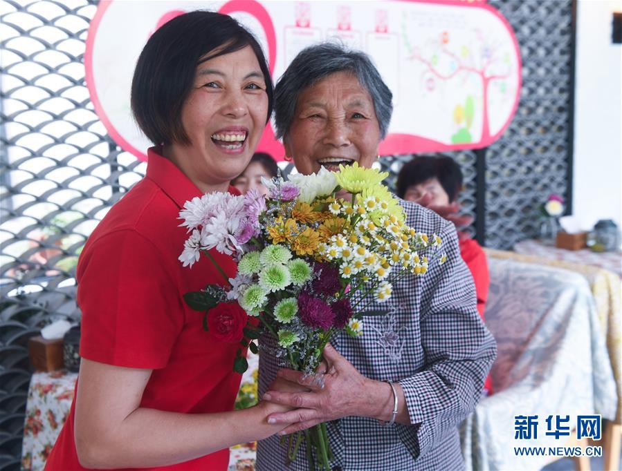 창싱현 샤오푸진 판리난(潘禮南)촌의 ‘부녀미가’에서 78세의 장진위(張瑾瑜·오른쪽)가 딸이 선물한 생화를 받고 있다. [5월 8일 촬영/사진 출처: 신화망]