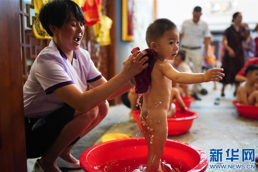 6월 22일, 주민이 난창시 둥후구 양쯔저우진 첸저우촌 촌문화대원에서 쑥물로 아이를 목욕시키고 있다. 이날 장시성 난창시 둥후구 첸저우촌 촌문화대원에서는 단오 민속 분위기의 행사가 열렸다. 사람들은 전통 민속을 체험하며 단오 명절 분위기를 만끽했다. [사진 출처: 신화망]