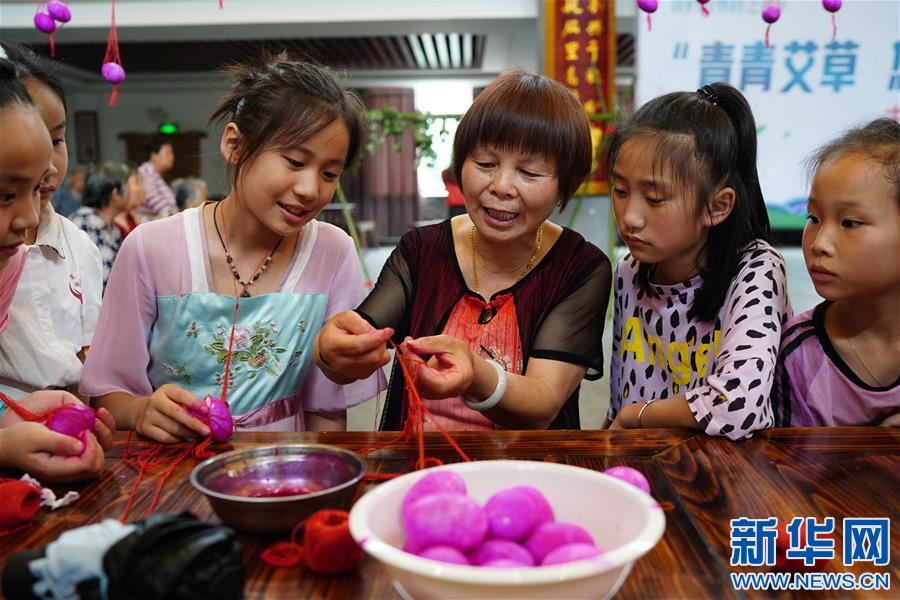 6월 22일, 주민이 난창(南昌)시 둥후(東湖)구 양쯔저우(揚子洲)진 첸저우(前洲)촌 촌문화대원에서 아이들에게 계란주머니(蛋袋) 만드는 방법을 알려주고 있다. [사진 출처: 신화망]