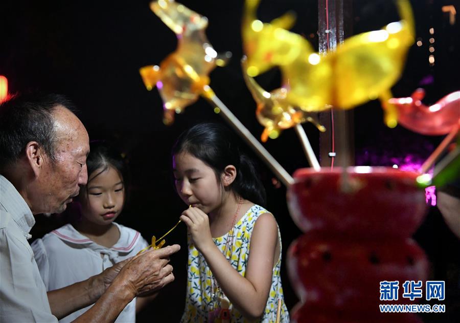 뤄양에서 추이탕런(吹糖人: 물엿으로 인형을 만드는 전통 놀이)을 즐기는 어린이 [7월 7일 촬영/사진 출처: 신화망]