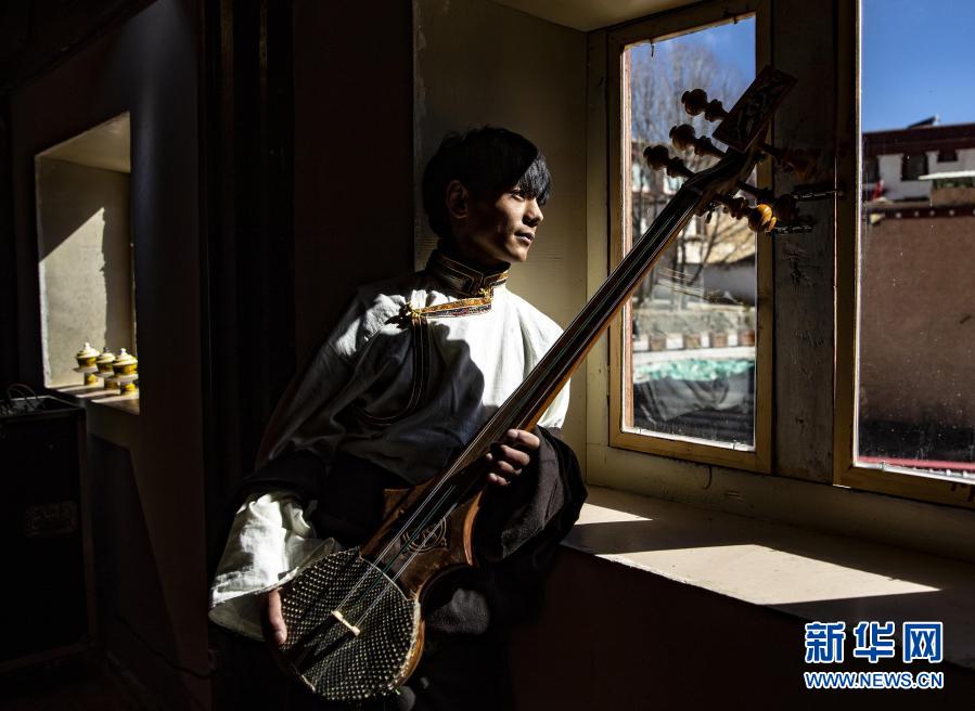 딩전이 장족 전통 악기인 자무녜를 안고 창밖 거리를 바라보고 있다. [12월 2일 촬영/사진 출처: 신화망]