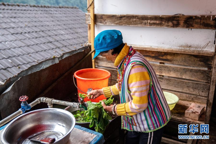 쿵당나 할머니는 부엌 문 앞에서 야채를 씻고 있다. [10월 31일 촬영/사진 출처: 신화망]