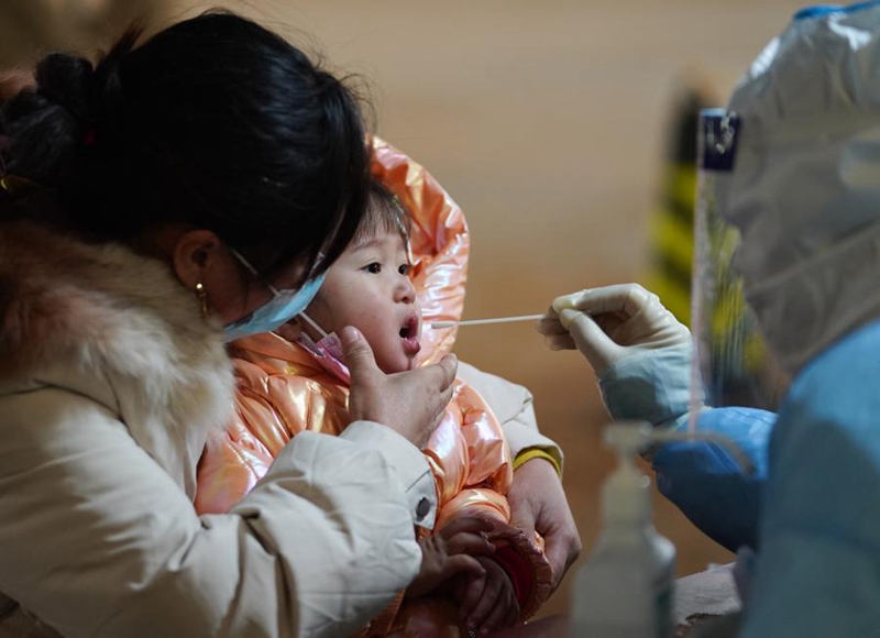 지난 20일 베이징시 다싱구 팡거좡진 핵산검사소에서 직원이 어린아이에게 핵산검사를 하고 있다. [사진 출처: 신화망]