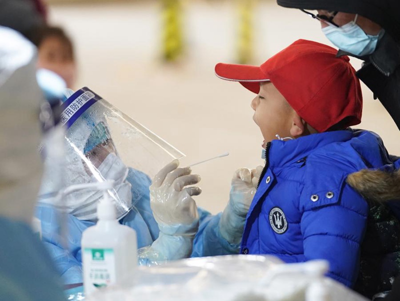 지난 20일 베이징시 다싱구 팡거좡(龐各莊)진 핵산검사소에서 직원이 어린아이에게 핵산검사를 하고 있다. [사진 출처: 신화망]