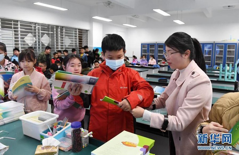 2월 27일, 광시(廣西) 난닝(南寧)시 빈후(濱湖)로 초등학교 교사가(오른쪽 첫 번째) 새 학기 교과서를 학생에게 나눠주고 있다. [사진 출처: 신화망]