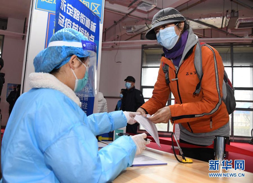 3월 14일, 베이징 하이뎬구 융딩루가도 임시 백신 접종소에서 주민(우)이 의료진에게 접종 주의사항에 대해 묻는다. [사진 출처: 신화망]