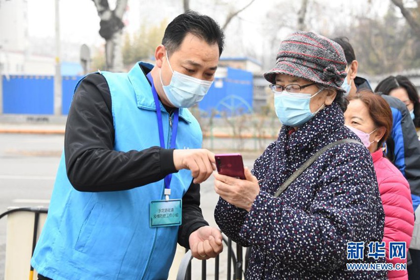 3월 14일, 베이징 하이뎬구 융딩루가도 임시 백신 접종소에서 현장 직원(좌)이 주민들의 문의 사항에 대답하고 있다. [사진 출처: 신화망]