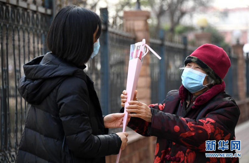 여성의 날 전날, 지역사회 직원인 류펀 씨(왼쪽)가 지역사회를 대표하여 타이위전 할머니께 꽃을 드렸다. [3월 7일 촬영/사진 출처: 신화망]