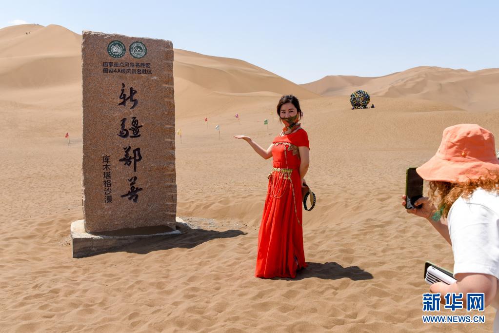 관광객이 신장 산산현 쿠무타거사막 관광지에서 기념 촬영을 하고 있다. [5월 15일 촬영/사진 출처: 신화망]