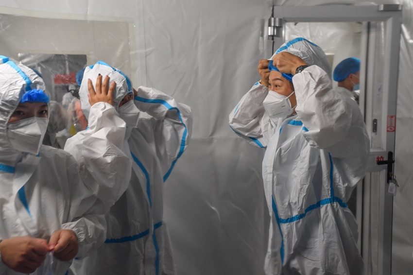 에어돔 임시 실험실 핵산 검사 처리 구역의 직원들이 방호복을 착용하고 있다. [6월 1일 촬영/사진 출처: 신화사]